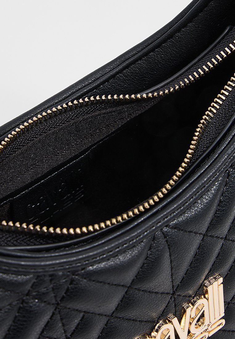 Schwarze, gesteppten Leder-Handtasche mit einem goldfarbenen Reißverschluss und Logo, ausgestattet mit einem strukturierten Innenfutter und runder Form.