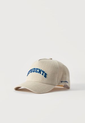 Gorra de béisbol beige con visera curvada, letras azules bordadas que dicen «STUDENTS» y un texto a juego en el lateral, sobre un fondo liso.