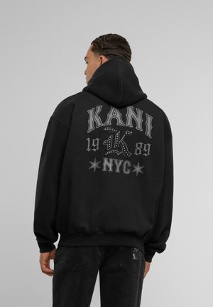 Black hoodie featuring "KANI" in large, stylized white letters on the back, with decorative stars, a relaxed fit, and ribbed cuffs.