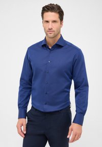 Blauwe overhemd met lange mouwen van textuurstof, met een spread collar, knoopsluiting en donkere knopen, gedragen met donkere broek.