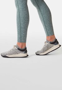 Šedé a bílé sportovní boty s lehkým pleteným svrškem, texturovanou podrážkou a reflexními prvky. Kombinované s tyrkysovými přiléhavými legínami.