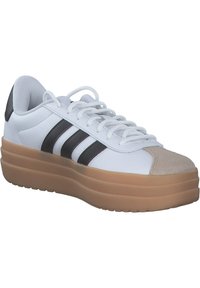 Białe sneakersy z czarnymi paskami i brązowym zamszowym noskiem. Posiadają grubą podeszwę platformową oraz teksturowaną cholewkę dla wsparcia i komfortu.