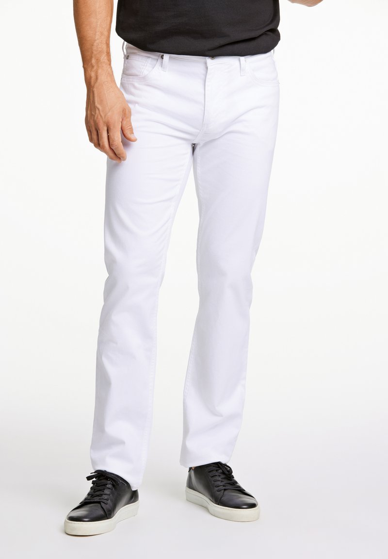 Vaqueros de denim blancos con corte recto, con cinco bolsillos y un clásico cierre de cremallera. Combinados con zapatillas negras. Textura suave.