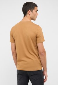T-shirt marron à manches courtes en tissu doux avec un col rond, une texture lisse et une coupe décontractée, présenté de dos sur un fond clair.
