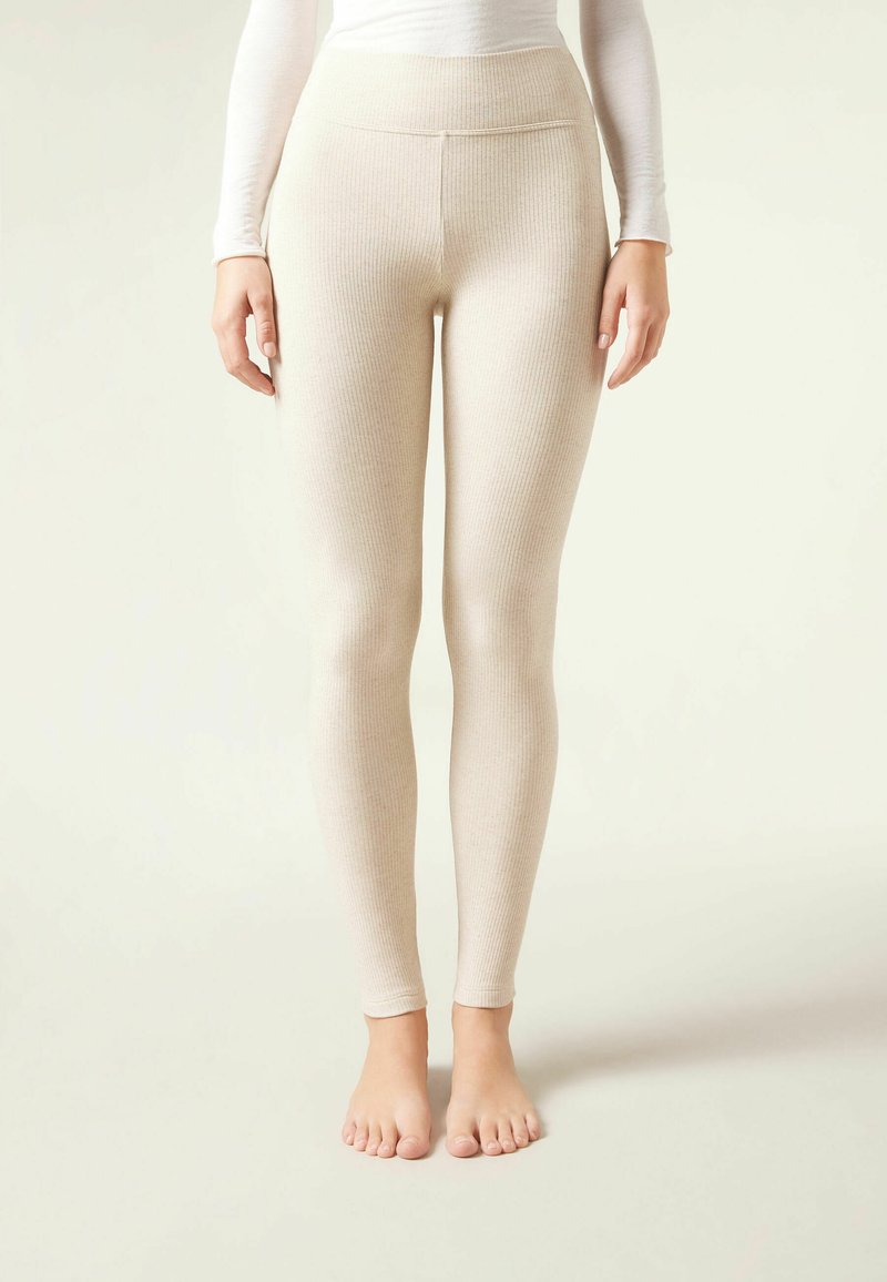 Beige ribbede leggings med høj talje, tætsiddende silhuet og glat tekstur, uden synlige sømme eller pynt.