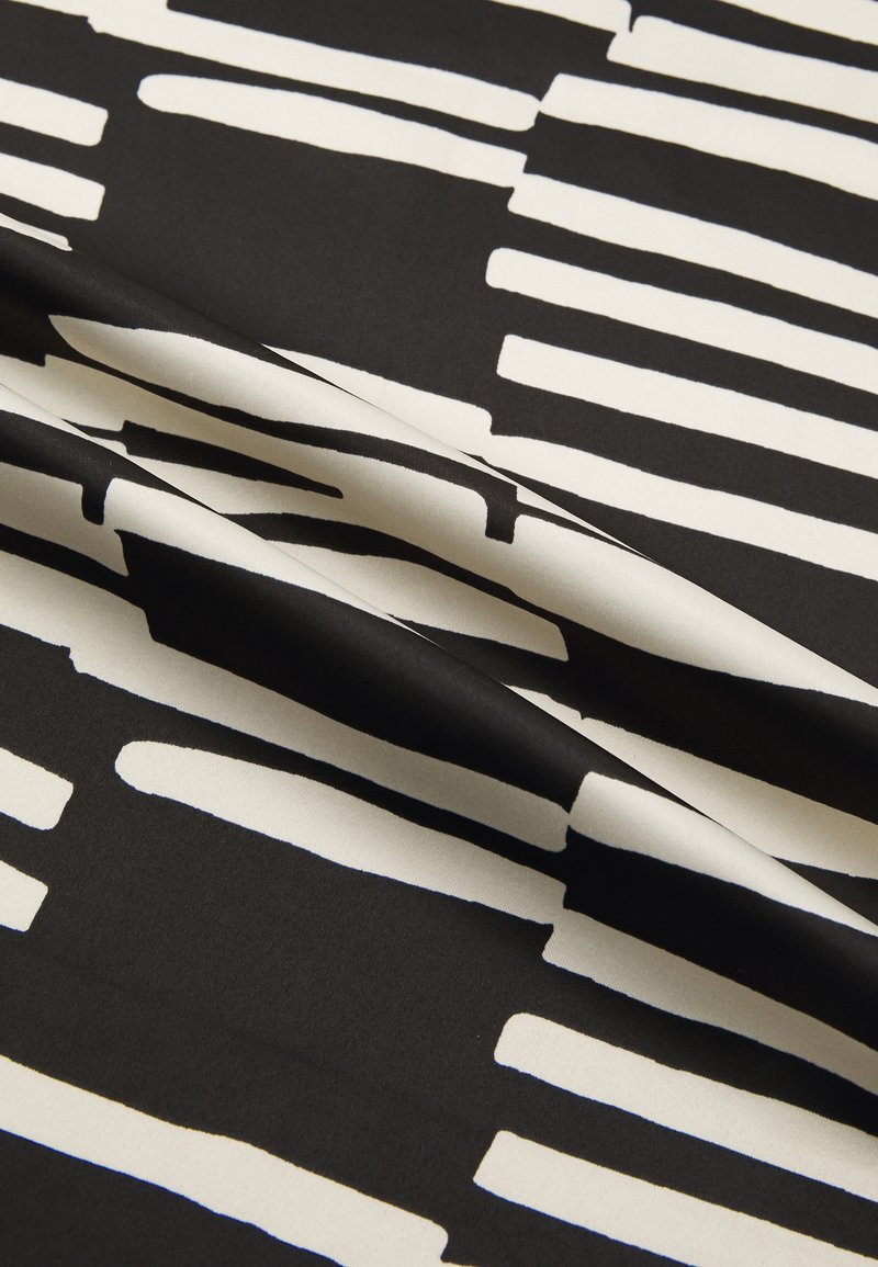 Czarna tkanina z odważnym białym wzorem pędzla, o gładkiej fakturze i różnej szerokości pasków, tworząca abstrakcyjny wzór.