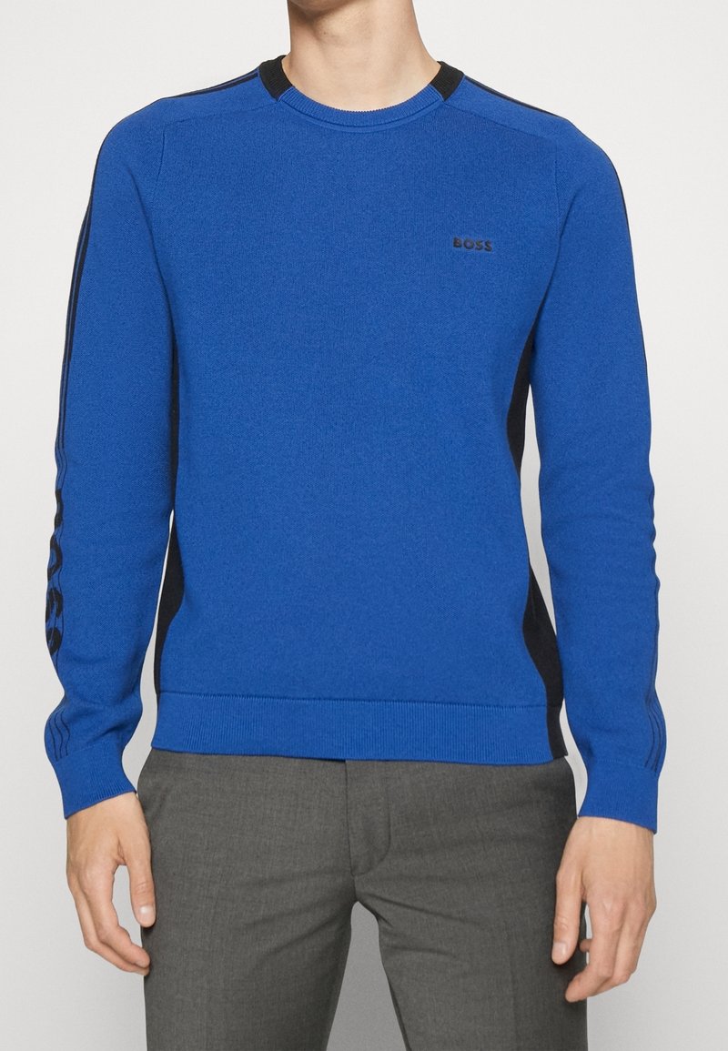 Maglione azzurro lavorato a maglia con scollo rotondo, dettagli neri sulle spalle e logo sul petto. Maniche e orlo a coste.