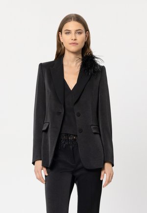 Schwarze Satin-Blazer mit Reverskragen, zwei vorderen Knöpfen, Seitentaschen und einer Feder-Akzentuierung an der linken Schulter. Taillierte Passform.