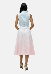 Vestido de mezclilla con un cuerpo sin mangas de color azul claro y una falda acampanada que va de blanco a rosa claro, ceñido en la cintura.