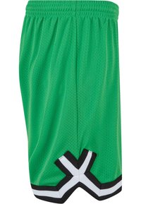 Groene mesh sportshorts met een gestructureerd oppervlak, voorzien van een zwart-wit accent aan de zoom in een kenmerkend kruispatroon.