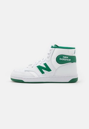 Biało-zielony wysoki sneaker New Balance z zielonym logo "N" i tekstem "new balance" po boku, pokazany od wewnętrznej strony.
