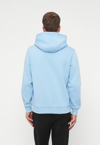 Ανοιχτού μπλε φούτερ φτιαγμένο από απαλό μείγμα βαμβακιού. Διαθέτει ευρύχωρη κουκούλα, ραμμένα μανίκια και τελείωμα. Ιδανικό για casual εμφάνιση.