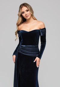 Off-Shoulder Samt-Abendkleid in tiefem Marineblau. Mit langen Ärmeln und einem plissierten Taillendetail sowie einem Oberschenkelhohen Schlitz.