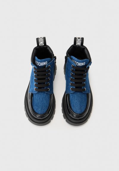 Zapatos de denim azul con cordones, con detalles de cuero negro y suelas de goma gruesa. Presentan un logo de Moschino en la lengüeta y la parte superior.