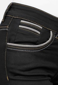Zwarte denim jeans hebben grijze accenten op de zak, contrasterende stiksels in geel en wit, en een gladde textuur.