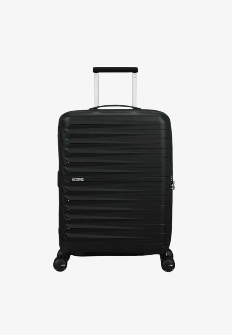 Valise rigide noire avec un motif zigzag texturé, poignée télescopique et quatre roues pour la mobilité. Comprend une fermeture éclair.