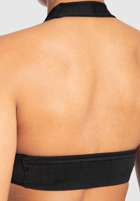 Zwarte halter-bra met een brede elastische band. De stof lijkt glad en rekbaar, met zichtbaar stiksel langs de randen.