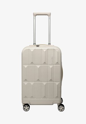 Lichtbeige harde koffer met getextureerde vierkanten, uitgetrokken telescopisch handvat, vier zwenkwielen en TSA-slot bovenop.