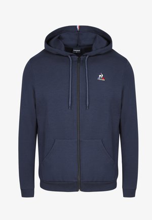 Sudadera con cremallera azul marino hecha de material de algodón suave. Presenta un cierre frontal con cremallera, dos bolsillos y un pequeño logotipo en el pecho.