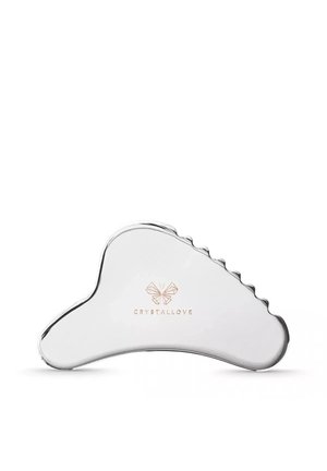 Gładkie, zakrzywione srebrne narzędzie gua sha z ząbkowanym brzegiem i logo "CRYSTALLOVE" z motywem motyla w centrum.