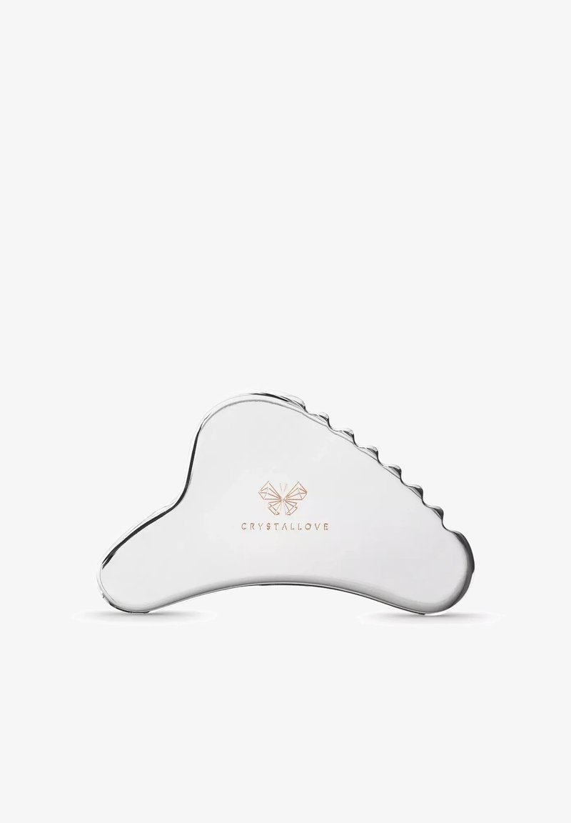 Outil gua sha en argent lisse et courbé avec un bord strié et le logo "CRYSTALLOVE" présentant un papillon au centre.