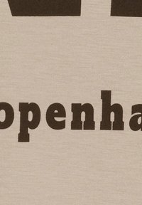 Bomullst-shirt i krämfärg med stora svarta blockbokstäver som stavar "Copenhagen." Mjuk textur med minimalistisk design utan grafik.