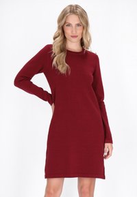 Vestito a maglia bordeaux con maniche lunghe, scollatura tonda e bottoni metallici decorativi sulla spalla. Tessuto a maglia liscia.