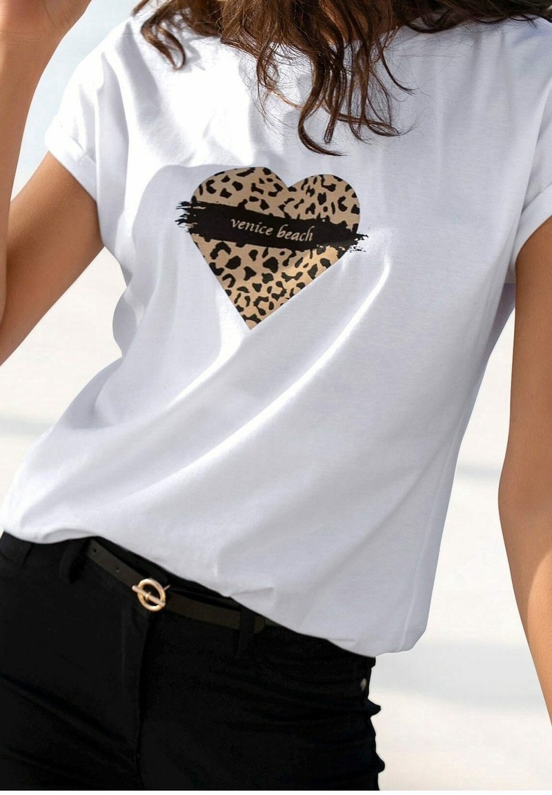 Camiseta de algodón blanca con mangas cortas que presenta un gráfico de corazón con estampado de leopardo y el texto "Venice Beach" en negro en el centro.