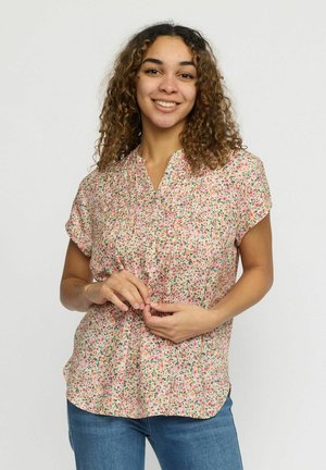Blomstret bluse i lys pink med korte ærmer og v-hals. Har små, flerfarvede blomstermønstre og en afslappet pasform.