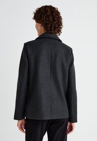 Cappotto di lana grigio scuro con colletto a revers, maniche lunghe e vestibilità sartoriale, caratterizzato da una texture liscia e linee pulite sul retro.