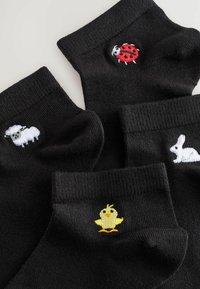 Crne anklets čarape s četiri različita vezena dizajna: bijela ovca, crvena bubamara, žuti kokoš i bijeli zec.
