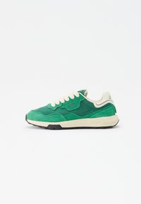 Green sneaker featuring a mix of suede and synthetic materials, textured panels, cream laces, and a white midsole with black outsole.