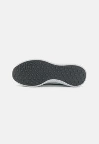Semelle de chaussure en caoutchouc noir avec un motif en vagues, présentant des trous circulaires pour l'adhérence, et un bord blanc le long du périmètre.