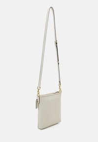 Světle šedá kožená crossbody taška s plochým obdélníkovým tvarem, dlouhým nastavitelným popruhem a zlatými akcenty kovových detailů. Uzavírá se zipem na vrchu.