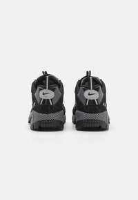 Adidași Nike negri și gri cu un superior din plasă și daim, talpă din cauciuc texturat, bucle de prindere și logo distinctiv pe călcâi.