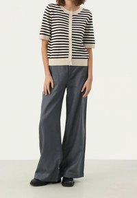 Striped cardigan in cream and navy with short sleeves and buttons, paired with wide-leg gray trousers and black shoes. Smooth texture.