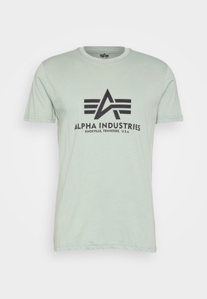 Ljusgrön bomulls t-shirt med rund halsringning, korta ärmar och svart tryckt "Alpha Industries"-logotyp med ikoniska designelement på framsidan.