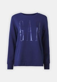 Sudadera azul marino con puños y dobladillo de canalé, que presenta un logo brillante de "GAP" en plata en la parte frontal. Material de algodón suave.