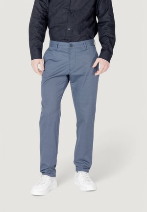 Pantaloni blu a fantasia con vestibilità su misura, dotati di chiusura a bottone e tasche laterali, abbinati a sneakers bianche.