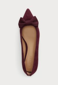 Burgundy mocka lägenhetssko med spetsig tå och en stor texturerad rosett vid framsidan, med en slät tan läderinlägg.