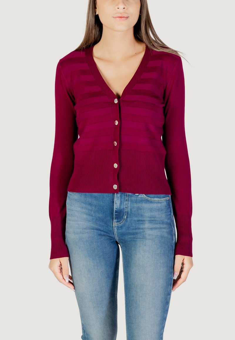 Cardigan bordeaux a V con una sottile texture a righe orizzontali, chiusura a bottoni e polsini a coste, abbinato a jeans azzurri chiari.
