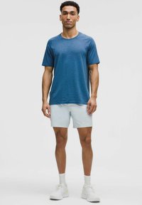 Blå tekstureret kortærmet t-shirt med rund hals, parret med lyseblå shorts og hvide sportsko. Enkel, afslappet design.