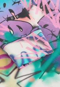Tissu de sweat-shirt multicolore présentant un mélange de motifs de style graffiti en rose, violet et teal avec des poignets côtelés.