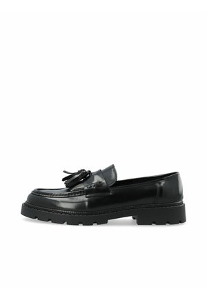 Mocassin en cuir noir brillant avec pompons et semelle épaisse et volumineuse, présenté de profil sur fond blanc.