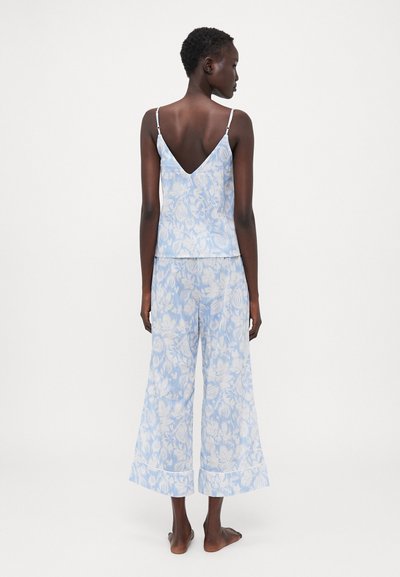 Camisola padrão floral azul com costas em V, combinada com calças largas. Feita de material leve, com alças ajustáveis e detalhes na barra.