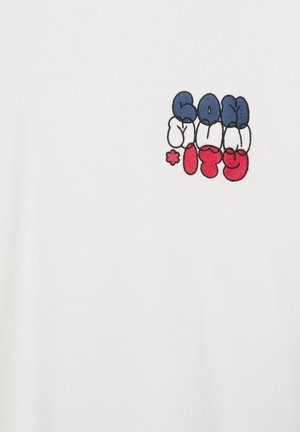 Tissu blanc avec un petit dessin brodé coloré de lettres abstraites en bleu, blanc et rouge, disposé en deux rangées.