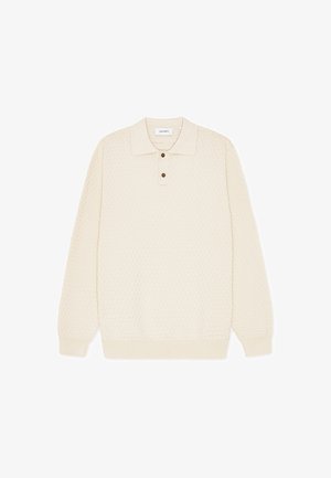 Kremfarget genser i strikket polo med teksturert mønster, lange ermer og tre-knappers slag. Mykt stoff med ribbekant nederst.