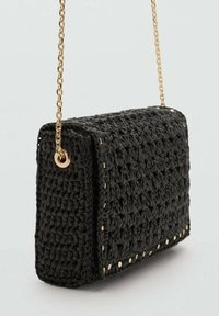 Borsa a mano nera intrecciata con forma rettangolare, tracolla in catena dorata e borchie dorate lungo i bordi, che mostra una superficie texture.