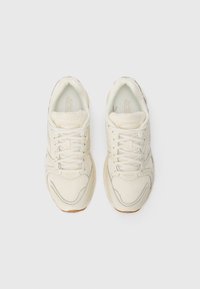 Un paio di scarpe da corsa Saucony color crema con tomaia in rete e sintetico viste dall'alto su uno sfondo bianco.
