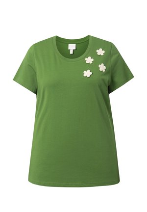 Vihreä lyhythihainen T-paita pyöreällä pääntiellä, jossa neljä valkoista virkattua kukka-aplikaatiota vasemman yläpuolen kohdalla.
